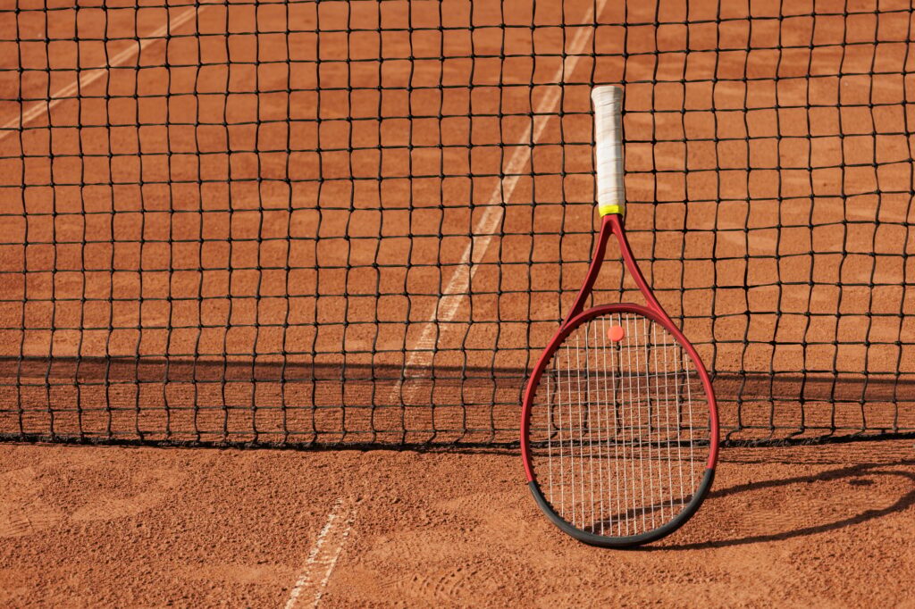 tennis racket is at net tennis court made of red clay soil with markings for game or competition